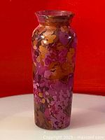 Front view of the vintage glass vase showing colorful hand painted floral patterns on cylindrical body with slightly flared rim.