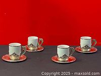 Set of four Italian Monopoly espresso cups in silver plate holders with matching silver saucers against red background