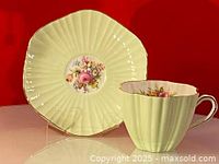 Front view of mint green Foley teacup and matching saucer showing floral design and gold rim