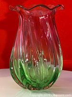 Front view of the vase showing the cranberry pink and green swirl glass with vertical ridges and bulbous shape.