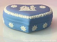 Photo showing the front and side view of the heart-shaped Wedgwood jasperware trinket box with white relief decoration on blue base.