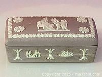 Top view of Wedgwood jasperware box showing white classical relief figures and floral details on purple base.