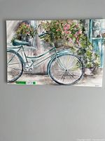 Full view of the textured canvas painting showing a teal vintage bicycle with large basket of pink flowers in front of rustic window.