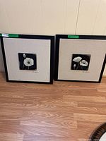 Two framed textured floral art prints titled 'Poppies' featuring white flowers on black squares, displayed side by side against a wall.