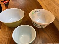 Four assorted mixing bowls in varying colors and sizes photographed on wooden table.