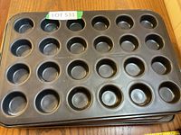Photo of one black mini muffin baking pan showing 24 round muffin cups in non-stick metal.