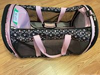 Top and side view of pink and black cat carrier with mesh panels and pink handles on wooden floor.