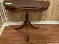 Front and side view of the wooden demilune table showing the drawer and rounded top shape.