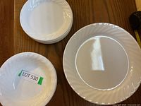 Top view of one dinner plate and a stack of smaller plates showing the swirl pattern on a glossy white surface.