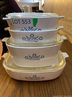 Stack of four Corning Ware casserole dishes in varying sizes with blue floral pattern and glass lids.