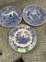 Three blue and white decorative plates from Spode Blue Room Collection with different patterns, showing detailed scenes with floral borders.