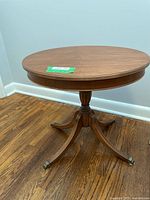 Front and side view of the round wooden occasional table showing the carved pedestal and claw feet.