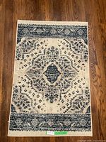 Full view of rectangular mat with blue and cream pattern on wood floor