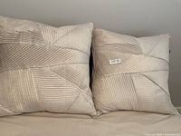 Pair of cream-colored sham pillows with feather down filling, textured geometric stitch pattern.