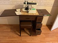 Full view of the Singer Merritt 6212 sewing machine set on the wooden cabinet with matching stool