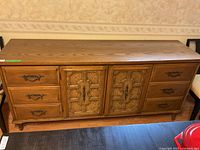 Front view of triple dresser showing six drawers on the sides and two central cabinet doors with ornate handles.