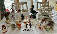 Overall view of assortment of animal figurines, decorative eggs, vases, jar, and birdcage arranged on table
