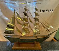 Front and side view of brass sailing ship model on wooden base, showing multiple sails and rigging.