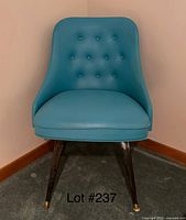 Blue mid century modern style accent chair with button tufted back and tapered wooden legs with brass caps.