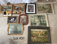 Top-down photo of all 12 framed outdoor and nature themed art pieces arranged on carpeted floor showing variety in frames, subject matter including landscapes, wildlife, and rustic scenes.