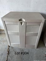 Front view of beige outdoor storage bin with closed double doors and flat lid showing the Suncast logo on the right door.
