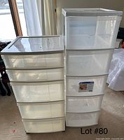 Photo shows two tall plastic storage units side by side, each with four drawers, in a carpeted room near a window.
