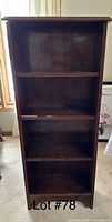 Front view of a tall wooden bookshelf with four shelves and a dark brown finish.
