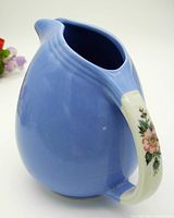 Blue ceramic jug with white handle decorated with a pink rose floral design