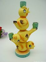 Front view of yellow ceramic Easter chicks stacked as totem pole candle holder with teal candle cups