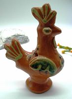 Front and side view of the glazed terra cotta rooster whistle showing colorful painted designs in folk art style with a glossy finish.