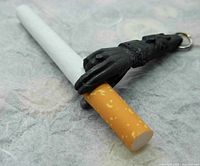 Close-up of the black finger tip protector holding a cigarette to demonstrate its function, showing detailed hand shape and textured surface.
