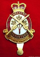 Front view of the cap badge showing the detailed enamel and crossed rifle design, maple leaf, crown, and inscription.