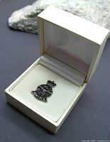 Silver service lapel pin displayed in an open white hinged box with satin lining.
