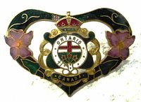 Front view of the early 1900s ornate Victorian Art Nouveau enamel brooch pin showing floral and heraldic details with some enamel loss near the crown.