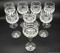 Eight 1970s Bohemia crystal hock wine goblets arranged in a compact group, showing their shape and clear geometric cut pattern on the bowls.