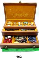 Wide open view of wooden jewelry box showing all three levels filled with assorted vintage costume jewelry.