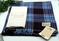 Full view of folded scarf with dust bag and tags shown on white background.