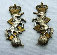 Front view of both RCEME collar dogs showing detailed rearing horse, crown, globe, and lightning bolt design with patina and wear.