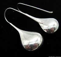 Pair of polished sterling silver puffy teardrop earrings with long wire hooks seen against a black background.