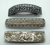 Top view of three vintage silver tone French barrettes showing detailed ornamental designs