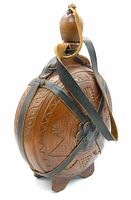 Front and side view of the wooden canteen flask showing leather straps, carved geometric and floral designs, and wooden stopper with a leather loop.