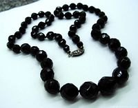 The full necklace showing the graduated faceted jet beads strung and knotted individually with a silver clasp.