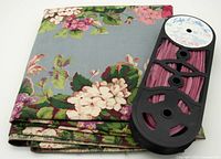 Folded vintage floral fabric with roll of pink velvet piping on top