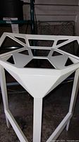 Close-up of white metal bar stool with geometric design