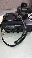 Photo showing Cobra 18WXST CB radio unit with coiled microphone attached, controls and front face visible.