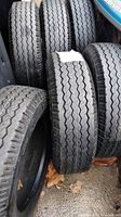Two used Goodyear Eagle LS size 245/50 R18 tires with visible decent tread and multiple other tires behind them.