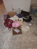 Photo showing entire lot of bags including wicker case, floral print totes, leather tote, and small pouches laid on beige carpet.