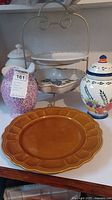 Overview of lot including cookie jars, plate stand with plates, and brown platter
