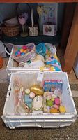 Lots of Easter decorations in white crates including colorful plastic eggs, baskets, and assorted figures