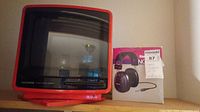 Full view of red Magnavox CRT TV and boxed Radio Shack headphones next to it.